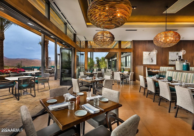 dining space featuring a mountain view, a tray ceiling, a notable chandelier, and wooden walls