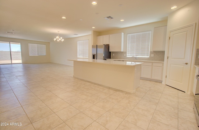 kitchen featuring white cabinetry, backsplash, stainless steel fridge, and a kitchen island