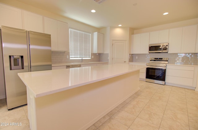 kitchen featuring sink, white cabinetry, a kitchen island, stainless steel appliances, and backsplash