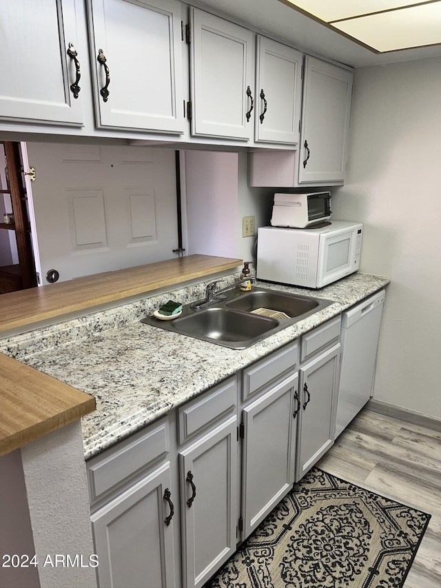 kitchen featuring gray cabinets, sink, white appliances, and light wood-type flooring