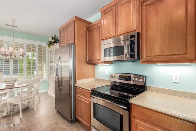 kitchen featuring a notable chandelier, stainless steel appliances, visible vents, brown cabinets, and decorative light fixtures