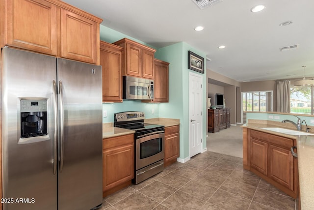 kitchen featuring visible vents, brown cabinets, stainless steel appliances, light countertops, and a sink