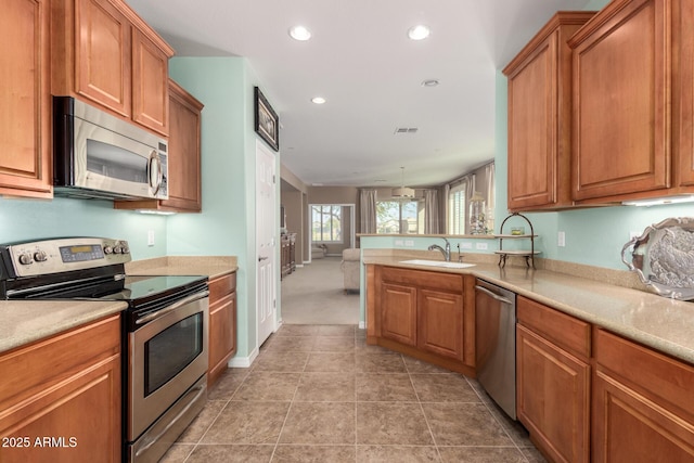 kitchen with brown cabinets, visible vents, stainless steel appliances, and a sink