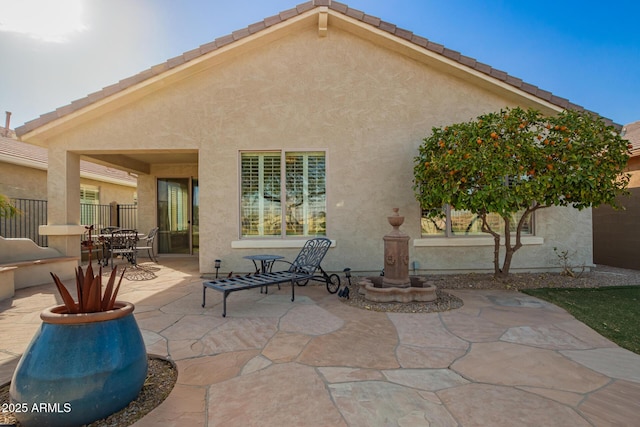 back of house featuring a tiled roof, fence, a patio, and stucco siding