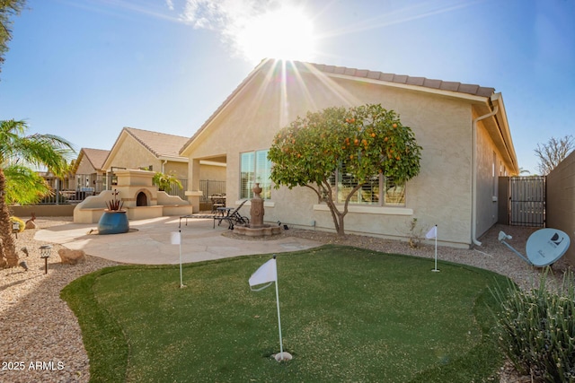 back of property with a patio, exterior fireplace, fence, and stucco siding