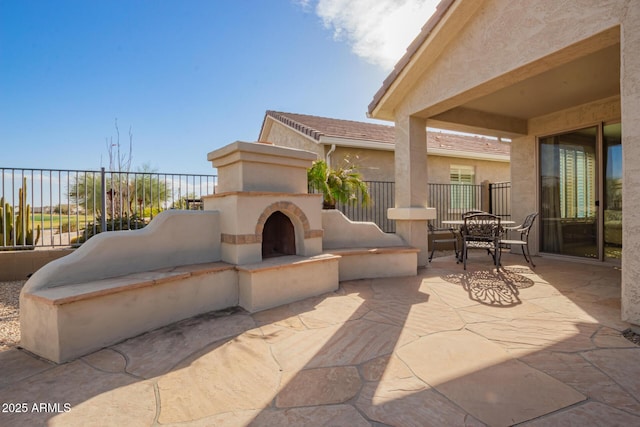 view of patio with fence and a tiled fireplace