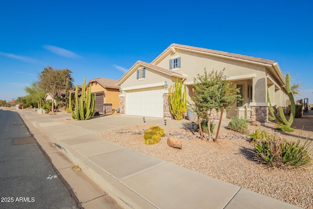 view of front facade with stucco siding, concrete driveway, a garage, stone siding, and a tiled roof