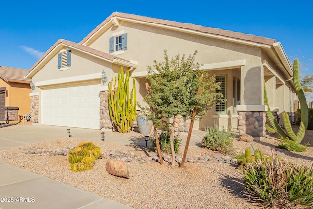 view of front of house with stucco siding, concrete driveway, an attached garage, stone siding, and a tiled roof