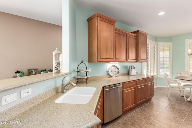 kitchen featuring brown cabinetry, a sink, stainless steel dishwasher, and light tile patterned floors