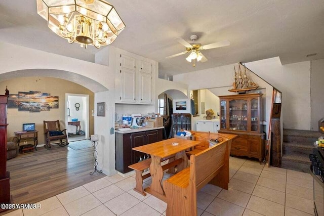 dining space featuring ceiling fan with notable chandelier, arched walkways, and light tile patterned flooring