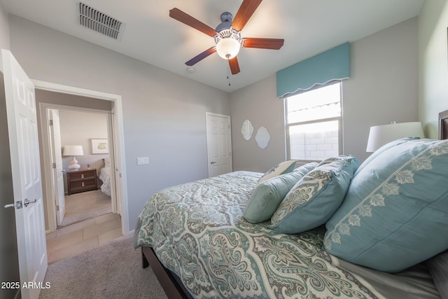 bedroom with light carpet, light tile patterned flooring, visible vents, and a ceiling fan