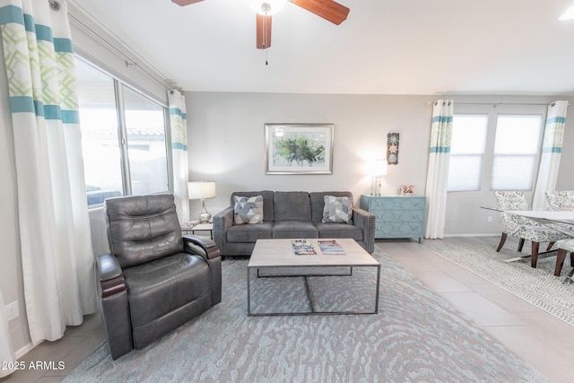 living area featuring ceiling fan, baseboards, and tile patterned floors