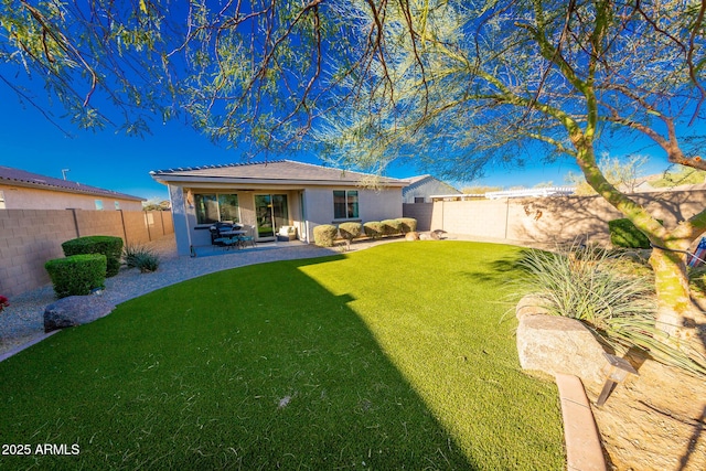 rear view of property with a yard, a patio area, a fenced backyard, and stucco siding