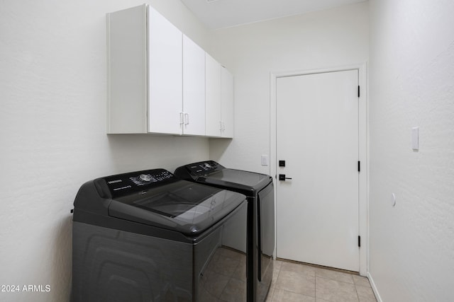 washroom featuring cabinets, washing machine and dryer, and light tile patterned floors