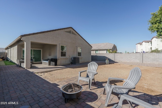 back of property with central AC, a patio area, and an outdoor fire pit