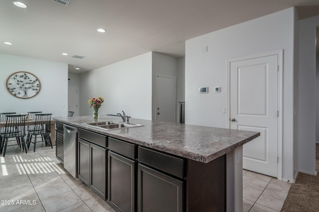 kitchen with sink, dark brown cabinets, a center island with sink, light tile patterned floors, and dishwasher