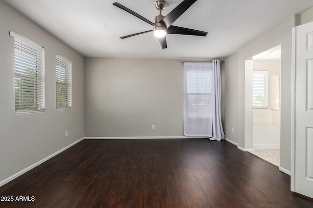 empty room with dark wood finished floors, plenty of natural light, baseboards, and ceiling fan