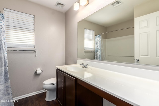 bathroom featuring baseboards, visible vents, vanity, and toilet