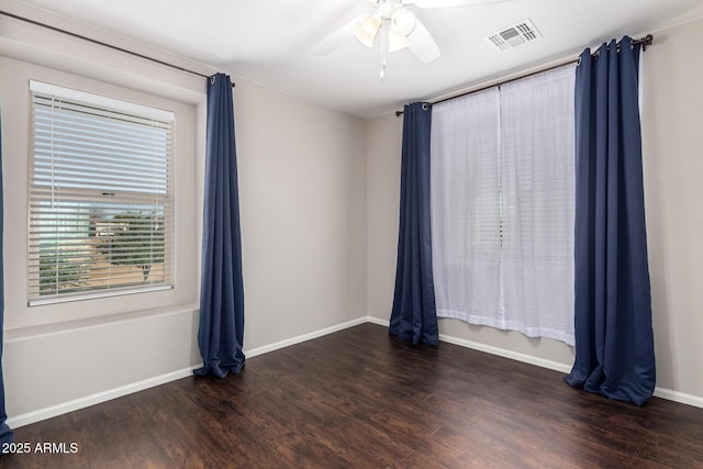 spare room with ceiling fan, wood finished floors, visible vents, and baseboards