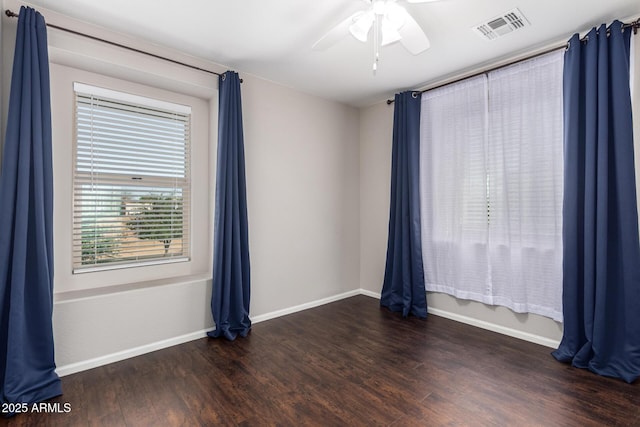 empty room with a ceiling fan, visible vents, baseboards, and wood finished floors