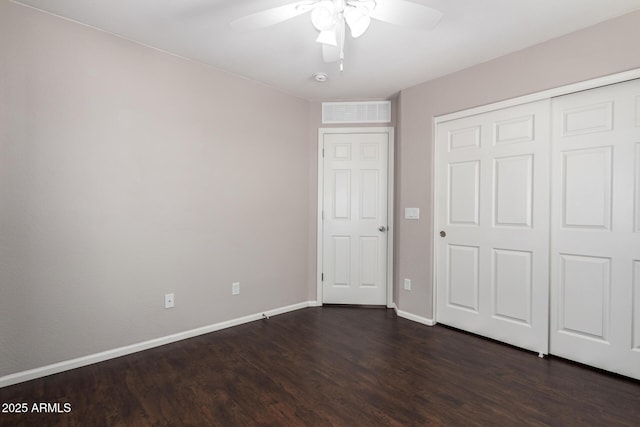 unfurnished bedroom featuring dark wood-style floors, a closet, visible vents, a ceiling fan, and baseboards