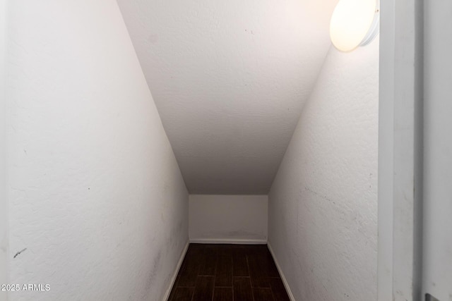 interior space featuring wood finish floors, a textured wall, and baseboards