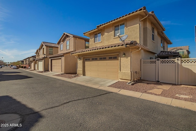 view of front of property featuring a garage, a residential view, a tiled roof, fence, and stucco siding