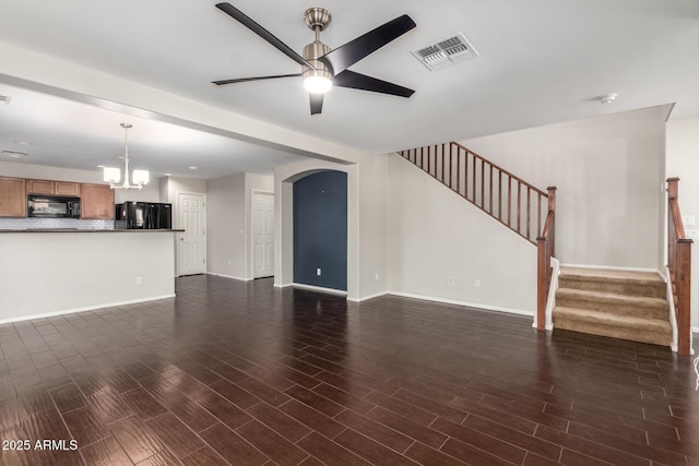 unfurnished living room with stairs, visible vents, wood finished floors, and ceiling fan with notable chandelier