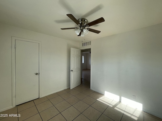 unfurnished bedroom featuring ceiling fan, light tile patterned floors, and a closet