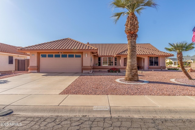 mediterranean / spanish-style home with stucco siding, an attached garage, driveway, and a tiled roof