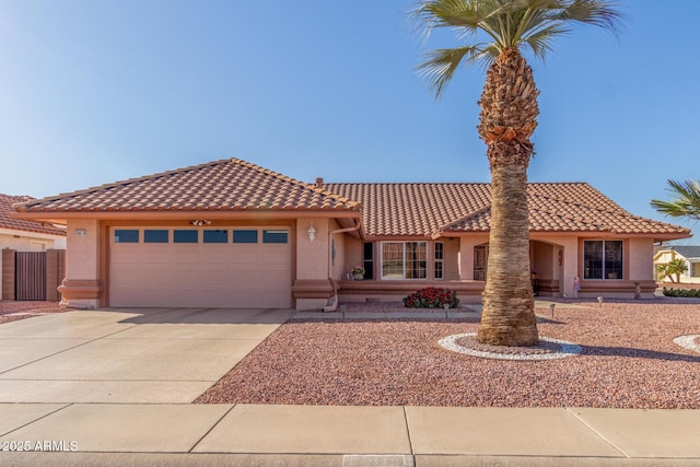 mediterranean / spanish-style house featuring a tile roof, an attached garage, driveway, and stucco siding