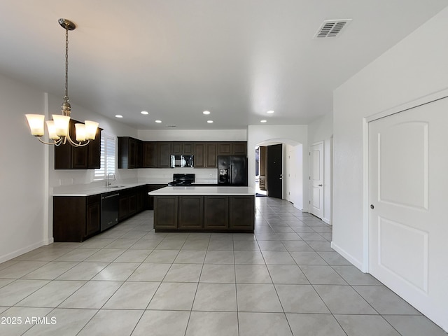 kitchen with a sink, visible vents, hanging light fixtures, light countertops, and black appliances