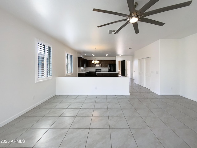 unfurnished living room featuring ceiling fan with notable chandelier, visible vents, and baseboards