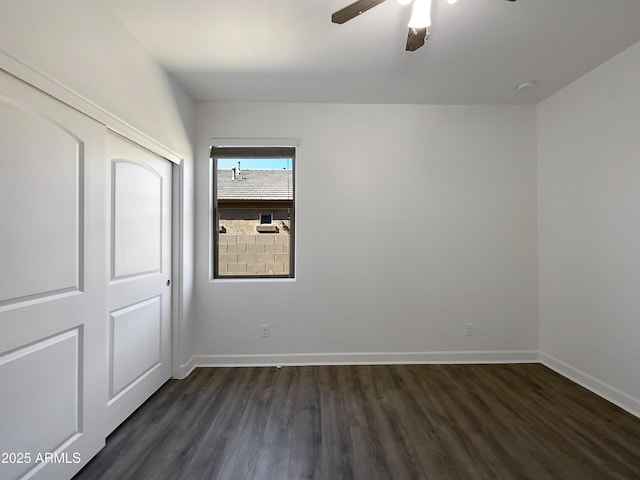 unfurnished bedroom featuring dark wood-type flooring, a closet, a ceiling fan, and baseboards