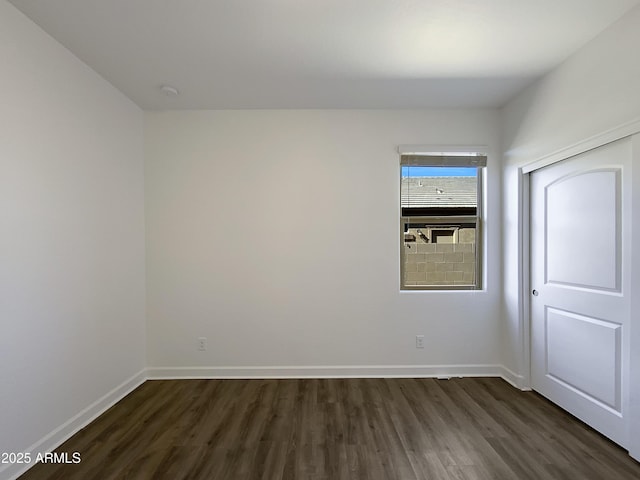 spare room with dark wood-type flooring and baseboards