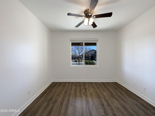 spare room with dark wood-type flooring, baseboards, and a ceiling fan