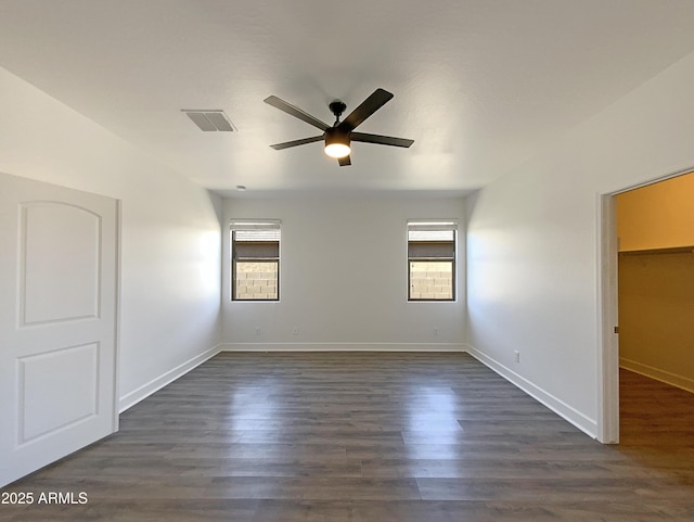 spare room featuring dark wood finished floors, a healthy amount of sunlight, visible vents, and ceiling fan