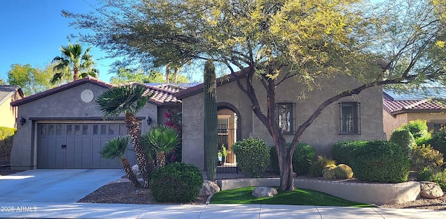 mediterranean / spanish house with a tiled roof, stucco siding, driveway, and a garage