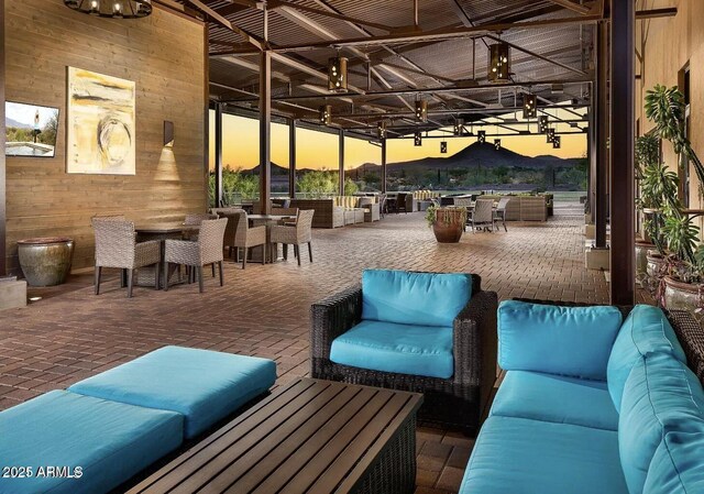 patio terrace at dusk featuring outdoor dining area, an outdoor hangout area, and a mountain view