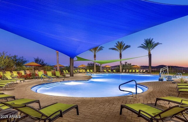 pool at dusk with a community pool, fence, and a patio area