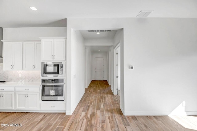 3310 Iron King Cir, Prescott, AZ 86301 - kitchen with stainless steel oven, light wood-style flooring, white cabinets, backsplash, and built in microwave