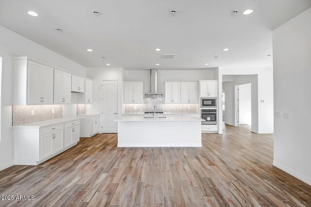3310 Iron King Cir, Prescott, AZ 86301 - kitchen with wall chimney range hood, black microwave, visible vents, light wood-style floors, and stainless steel oven