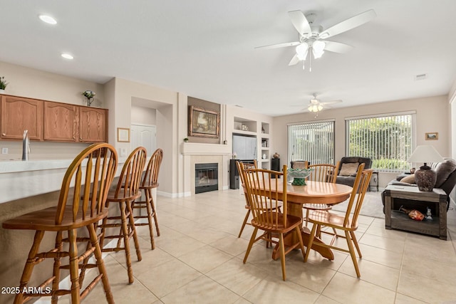 dining space with a tiled fireplace, light tile patterned floors, and built in features