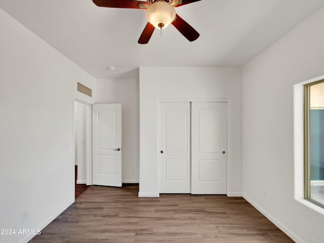 unfurnished bedroom with ceiling fan, a closet, and hardwood / wood-style floors