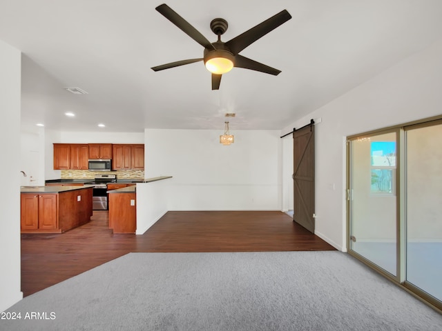 kitchen featuring dark colored carpet, appliances with stainless steel finishes, ceiling fan, a barn door, and pendant lighting