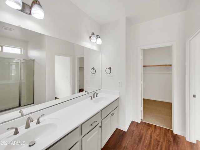 bathroom featuring a shower with door, hardwood / wood-style floors, and dual bowl vanity