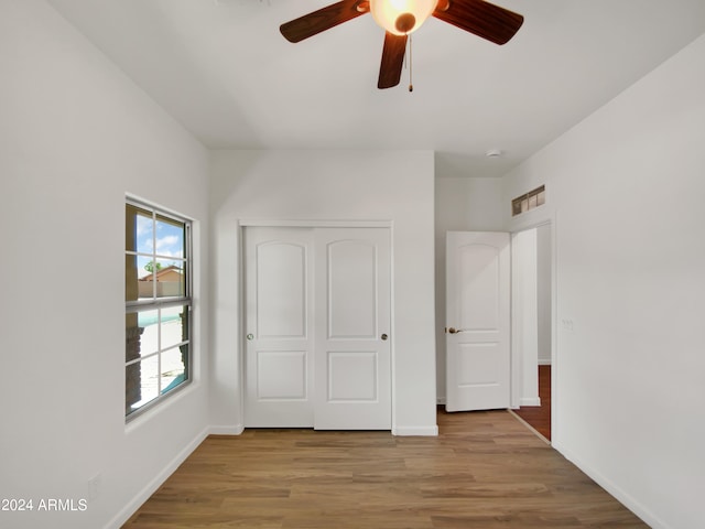 unfurnished bedroom featuring light hardwood / wood-style floors, a closet, and ceiling fan