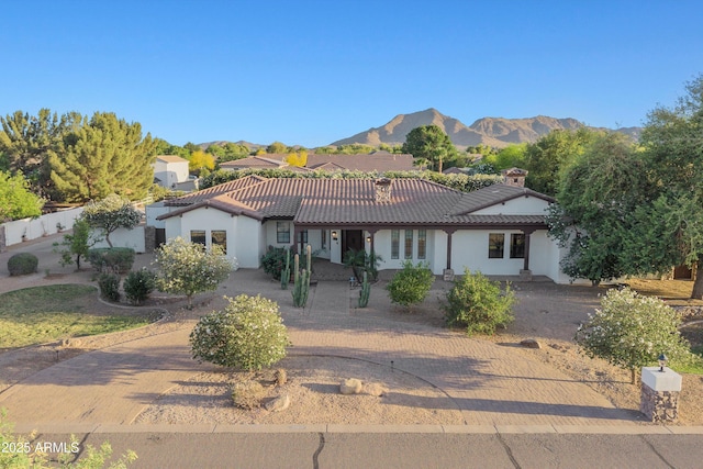 view of front of house featuring stucco siding, a mountain view, a tiled roof, and a chimney