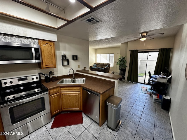 kitchen with sink, ceiling fan, a textured ceiling, appliances with stainless steel finishes, and light tile patterned flooring