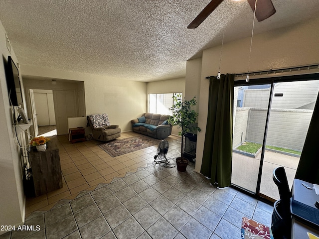 living room featuring ceiling fan, tile patterned flooring, and a textured ceiling